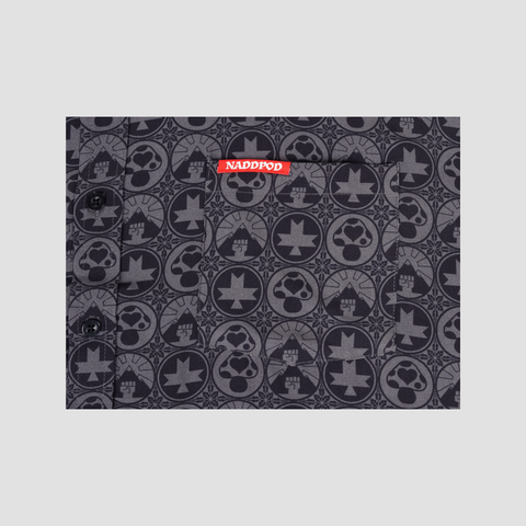 Closeup of white NADDPOD text on red background on front pocket of black buttondown