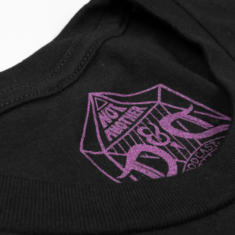 closeup of purple NADDPOD logo on inner neck of black tee