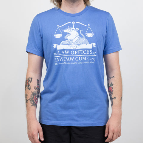 Blue shirt on male model with text "The LAW OFFICES OF PAW PAW GUMP, ESQ. "The Scramble Man with the Scramble Plan."" with graphic of opossum in front of balance